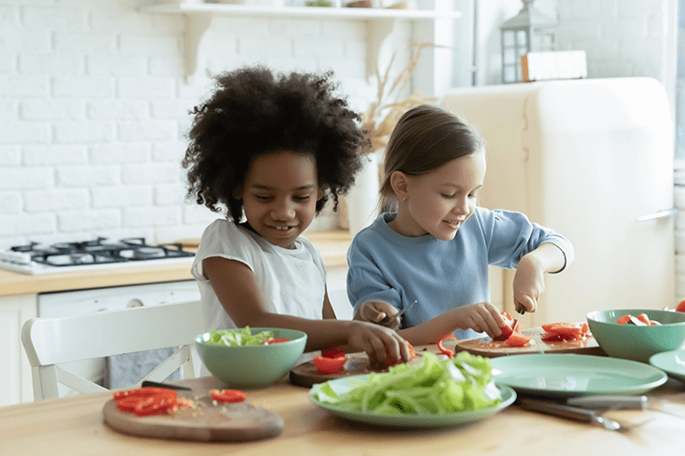 two young children prepare vegetables in a kitchen