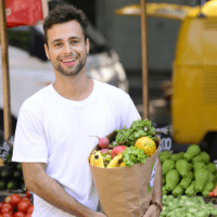 a man smiles holding a bag of produce