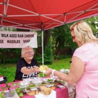 a farmer hands a product to a customer at a farmers market