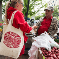 a farmer assists a customer at a market