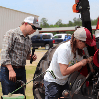 two people examine a tractor