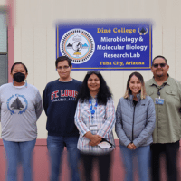 students and faculty smile in front of the research building