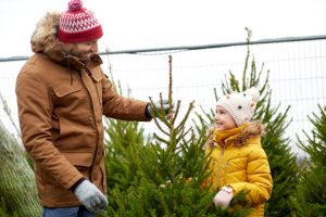 a father and daughter look at a Christmas tree together